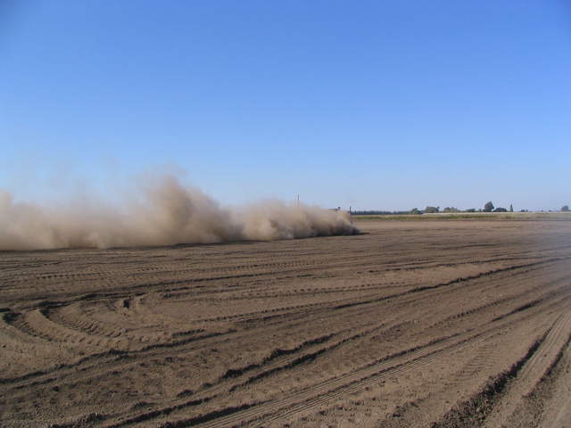 Cloud of dust from tractor tilling field