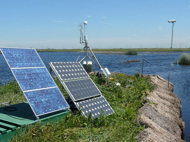 Solar panels and tripod tower protected from safflower bales