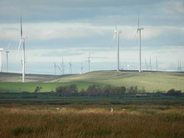 Wind turbines over green fields on a mostly overcast day