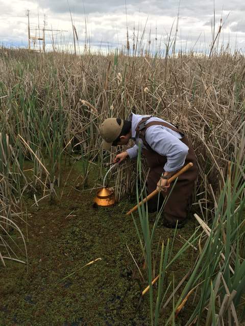 Camilo disturbing the wetland soil with a hoe and collecting methane in the funnel (precipitation bucket funnel), trying to collect enough to make an appreciable flame. 
