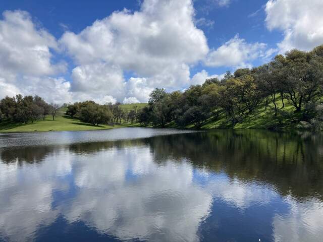 The pond is full, green hills, white clouds, blue sky