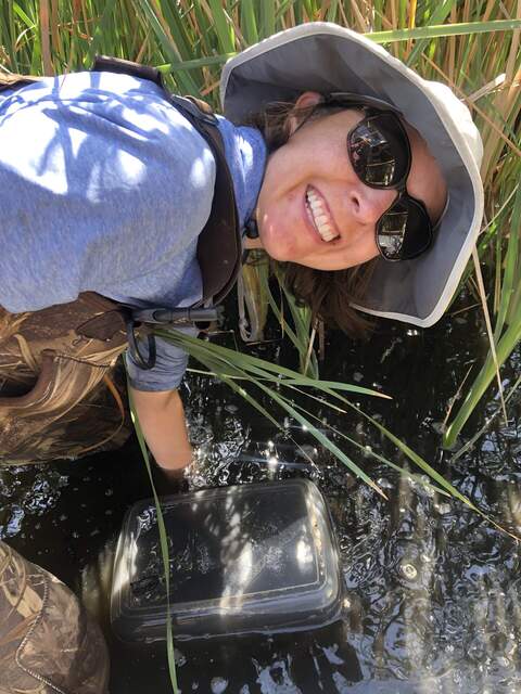 Kyle collecting sediment gas samples using a plastic tub