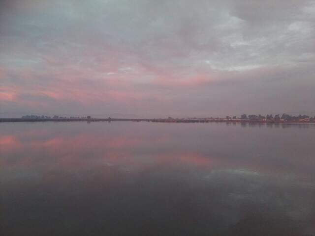 Pink morning clouds reflected in the water